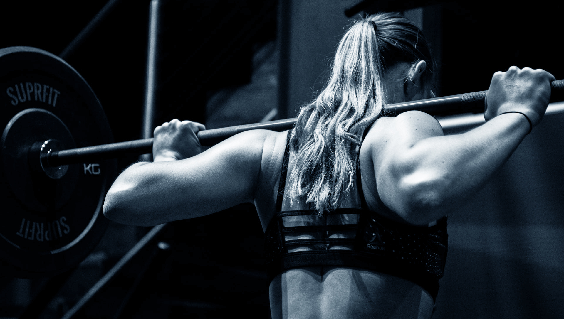 A woman lifting a dumbbell at a gym.